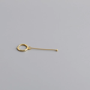 Gros plan du poinçon S925 sur une boucle d'oreille minimaliste pendante dorée