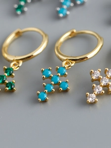 Vue macro des boucles d'oreilles croix dorées avec zircons colorés et fini poli