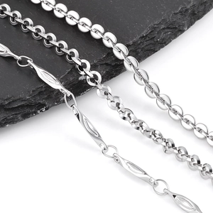 Detailed macro view of three silver stainless steel chain styles on grey stone texture