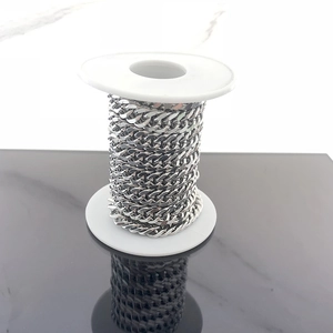 Close-up of bulk silver stainless steel curb chain on a white plastic spool for DIY jewelry