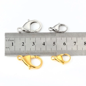 Comparaison de fermoirs mousquetons or et argent en 12mm et 21mm avec une règle en métal