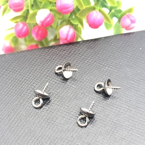 Detailed macro view of four stainless steel pearl cup bails on black leather background