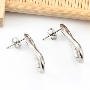 Polished silver irregular wave stud earrings with fluid design on wooden tray