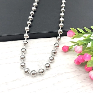 Minimalist silver stainless steel bead chain necklace displayed on modern textured background
