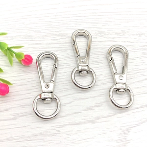 Three silver swivel lobster clasps for bags and keychains on white wood background