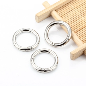 Three round silver alloy spring gate rings for bags and keychains on white background