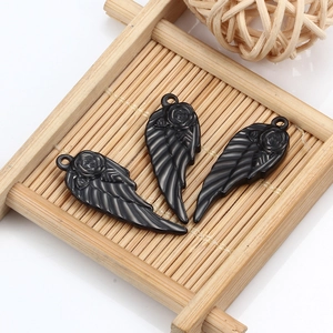 Three black resin rose feather wing pendants displayed on a rustic bamboo wooden tray