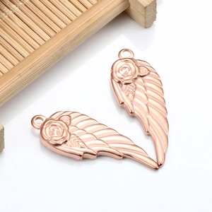 Macro view of rose gold stainless steel wing pendants with delicate rose flower detailing