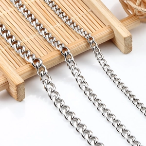 Close-up of polished stainless steel curb chains in three distinct widths on wood