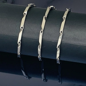 Minimalist silver stainless steel geometric link chains displayed on a black cylindrical stand