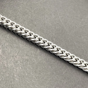 Macro detail of silver stainless steel Franco chain showing intricate braided link texture