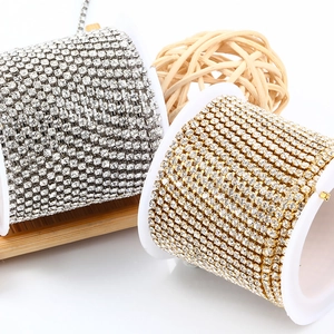 Macro detail of 3mm gold and silver rhinestone claw chains on white plastic spools