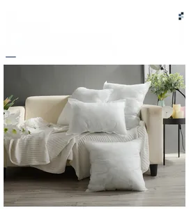 Verschiedene Größen weißer quadratischer und rechteckiger Kisseninlays auf einem Sofa