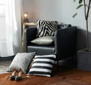 Détail de housses de coussin à rayures, léopard et satin sur un fauteuil en cuir