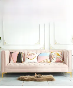 Set of four pink and gold geometric throw pillow covers on a velvet sofa with modern patterns