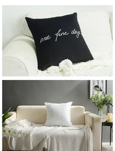 Detail of black cotton pillowcase with 'one fine day' embroidery and white inner insert