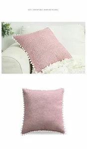 Dettaglio di una fodera per cuscino a righe con frangia decorativa a pompon sul divano