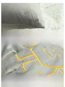 Close-up of grey velvet pillow cover with gold embroidery and fine stitching detail
