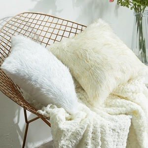 White and cream plush faux fur throw pillows with gold tinsel on a modern metal chair