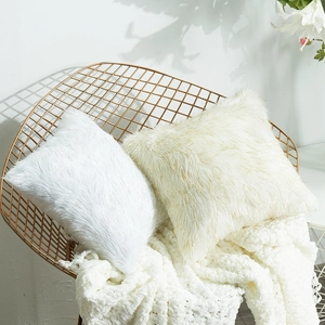 Luxurious white and cream faux fur decorative pillows on a stylish golden chair