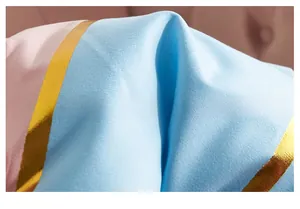 Macro detail of laser gold foil ribbon stitched on pink and blue decorative cushion cover
