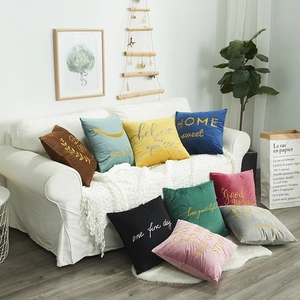 Modern embroidered velvet pillows in multiple vibrant colors on a minimalist white sofa