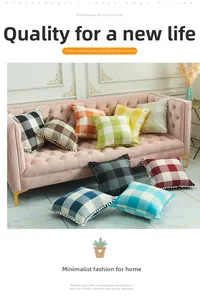 Close-up of colorful checkered linen cushion covers with pom-pom edges on a sofa