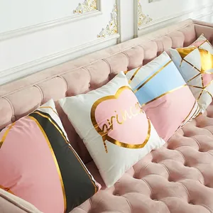 Modern laser gold foil cushion covers with geometric patterns on a plush pink sofa