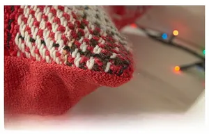 Close-up of red and white tweed knitted cushion cover with warm festive lighting