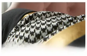 Detail of houndstooth fabric with gold metallic trim on a modern pillow cover