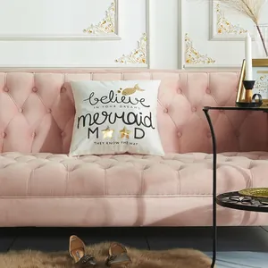 Modern white pillow cover with gold laser foil lettering on a pink velvet sofa
