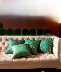 Detail of four green velvet cushion covers with gold accents on a pink sofa