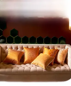 Close-up of geometric abstract cushion covers in orange and gold with shiny textures