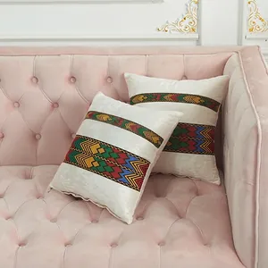 Beige velvet throw pillow covers with colorful ethnic embroidery on a pink sofa