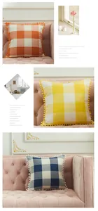 Close-up of linen checkered pillowcases with decorative pom-poms on a pink sofa