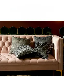 Detailed view of four modern geometric textured cushion covers on a velvet sofa