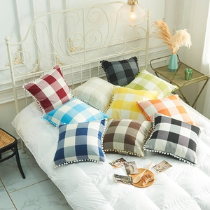 Modern linen plaid pillow covers with pom-pom edges displayed in a cozy bedroom setting