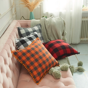 Buffalo plaid pillow covers with pom-poms shown in four colors on a modern sofa