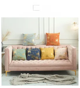 Detail view of colorful velvet throw pillows with golden palm tree prints on a sofa