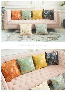 Detail of luxury geometric gold foil pillow covers on a pink tufted sofa