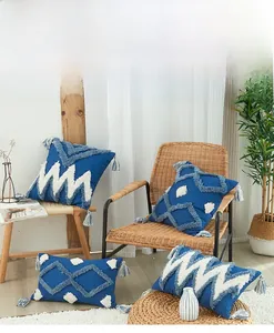 Détails des textures géométriques tuftées et des glands sur housses de coussin bleues