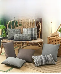 Housses de coussin en lin à carreaux marron et gris posées sur une chaise tressée