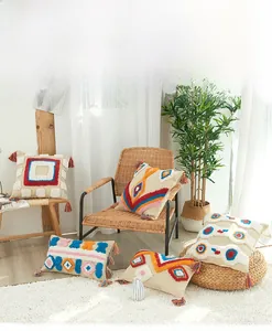 Détail de la housse de coussin bohème en coton avec motifs géométriques touffetés colorés