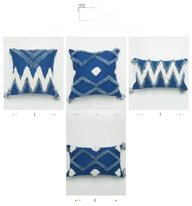 Détail des motifs géométriques tuftés et pompons sur les housses de coussin bleu marine