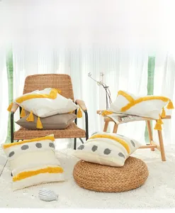 Detailed view of yellow and gray geometric tufting with cotton tassels on pillow cover