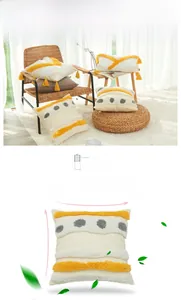 Detail of bohemian cotton tufted pillowcase with geometric embroidery and yellow tassels