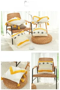 Detail of bohemian cotton tufted pillow cover with yellow geometric embroidery and tassels