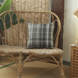 Housse de coussin en lin à carreaux noir et blanc sur un banc en rotin naturel