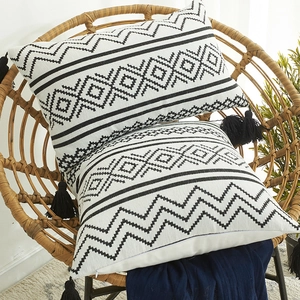 Bohemian geometric chenille cushion cover with black tassels on a rattan chair
