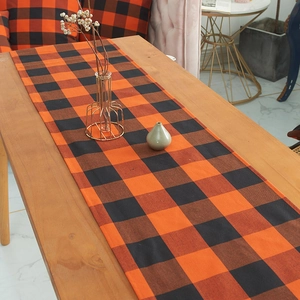 Classic orange and black buffalo plaid table runner on a rustic wooden dining table
